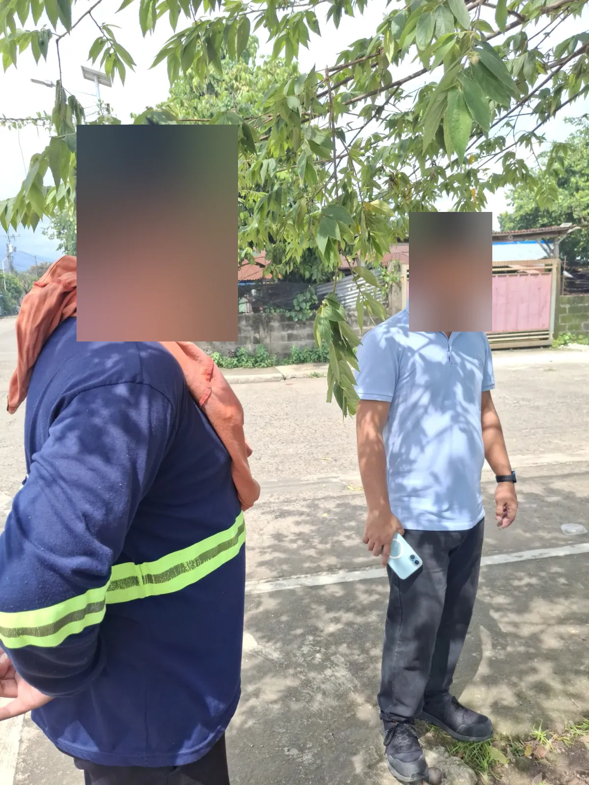 Two people standing in the shade beside the street during the relocation survey visit