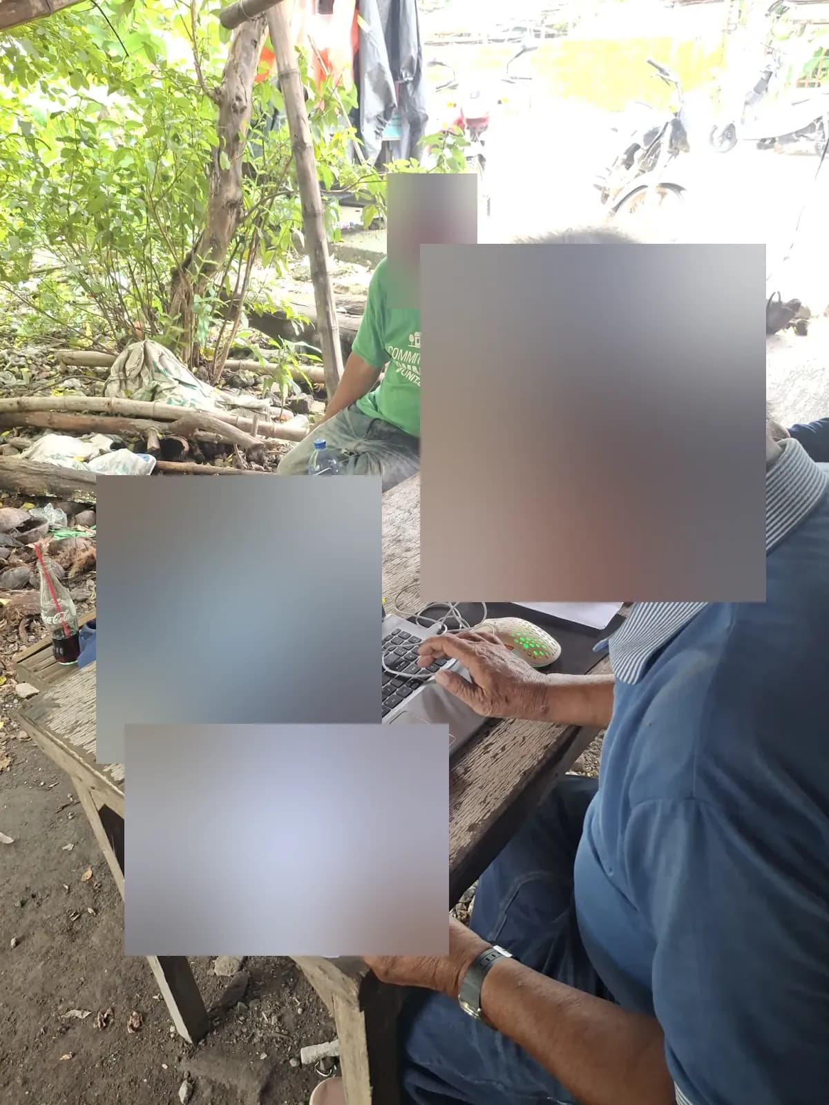 Surveyor reviewing printed documents beside a laptop at a sheltered outdoor worktable