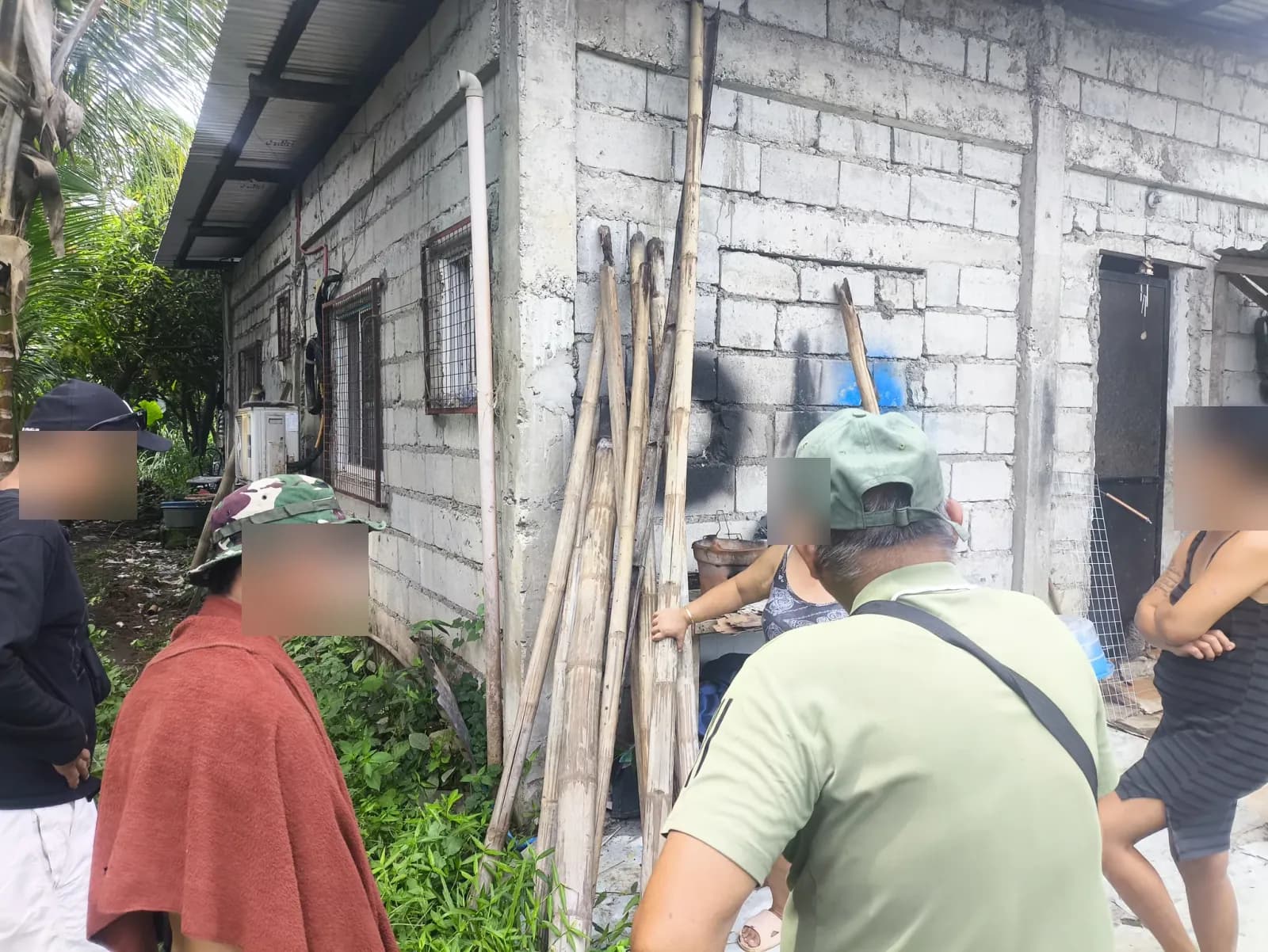 People discussing relocation survey fieldwork beside a concrete-block home in Silay, Negros Occidental