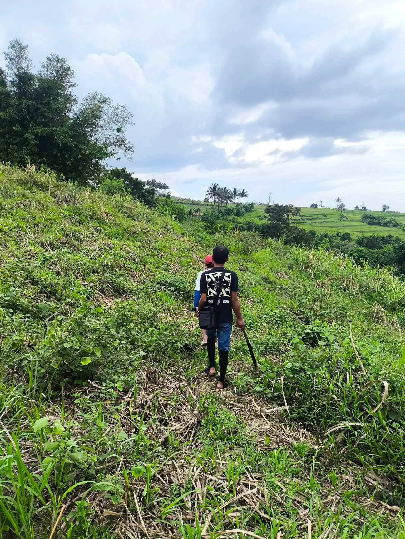 Leonor Surveying Services field crew traversing a hillside with survey equipment in Silay, Negros Occidental